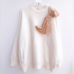 The sweater has a velvet bow on the shoulder